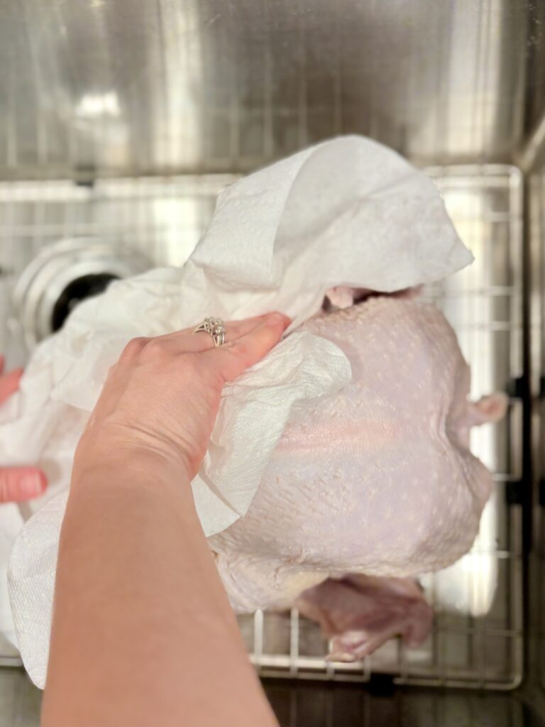 a turkey being dried with paper towels.