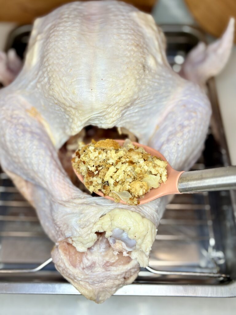 a turkey in a roasting pan being stuffed with classic stuffing 