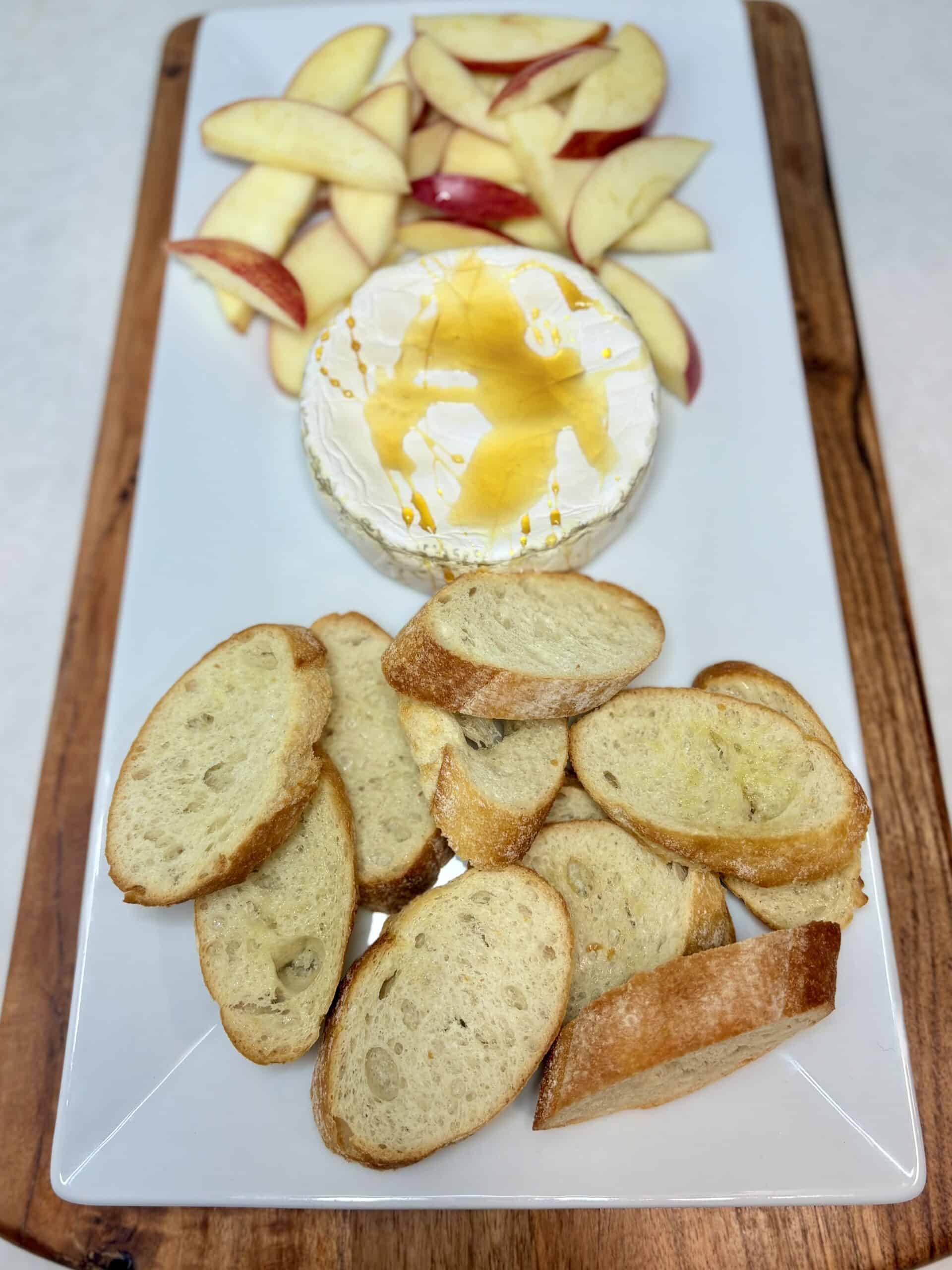 Baked brie on a plate with crostini and apple slices