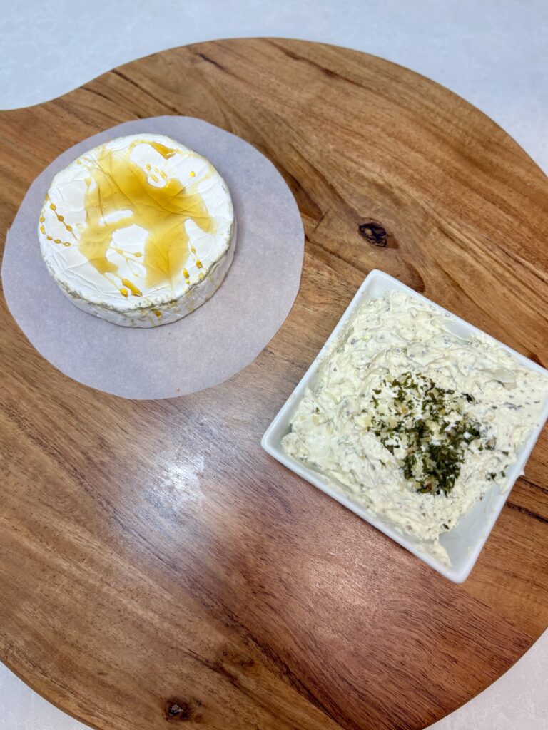 baked brie and cheese spread on a board on a counter