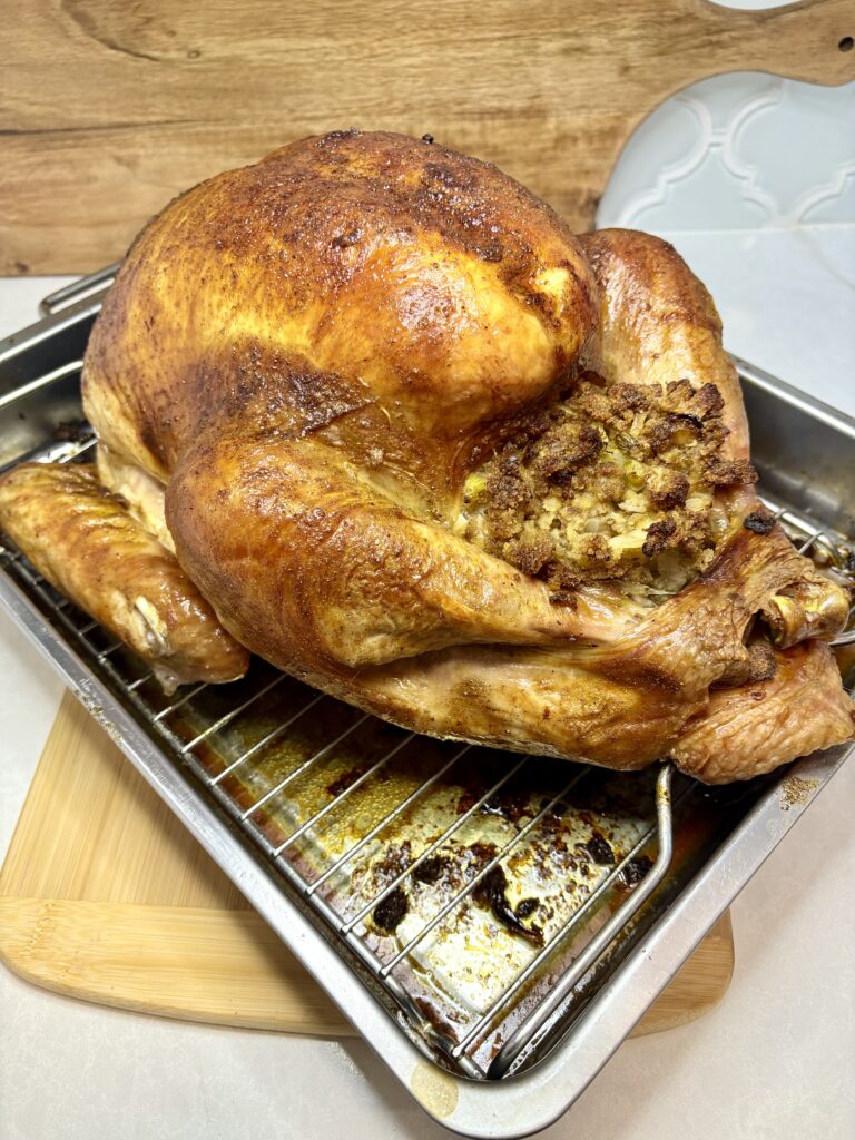 a whole roasted, stuffed, turkey in a roasting pan on a counter