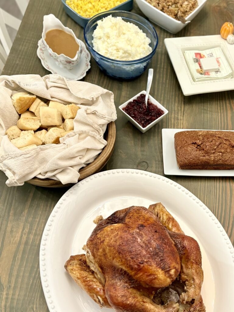 an oven roasted turkey on a platter with side dishes in different bowls on a table