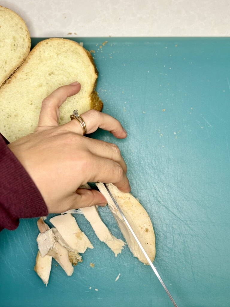 turkey on a cutting board being sliced into bite size pieces 