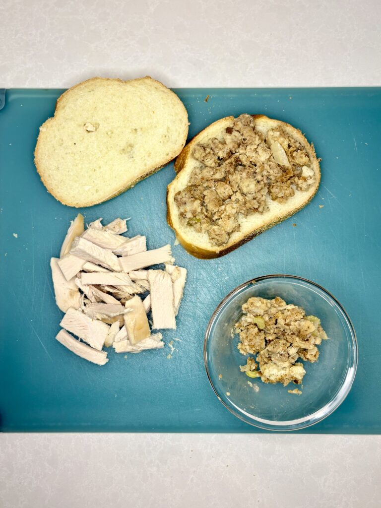 a cutting board with bread, stuffing, and turkey 