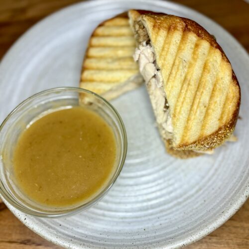 a pressed sandwich on a plate with gravy