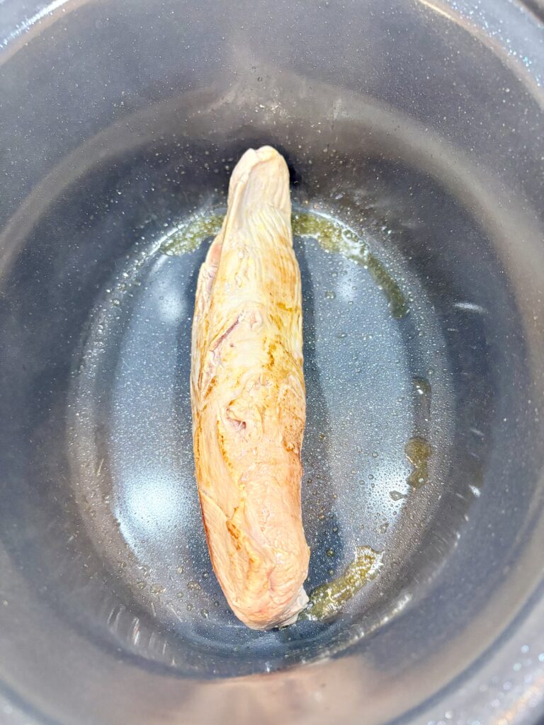 a pork tenderloin in a pan being browned on each side