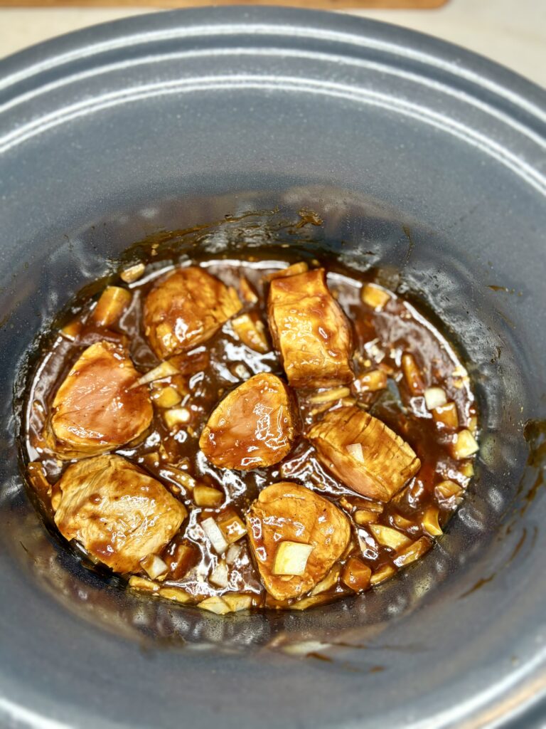 pork tenderloin pieces in a slow cooker with onions and barbecue sauce