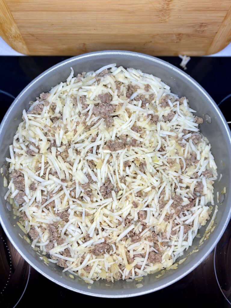 shredded hash brown  potatoes stirred in to pan on stove with sausage and onion