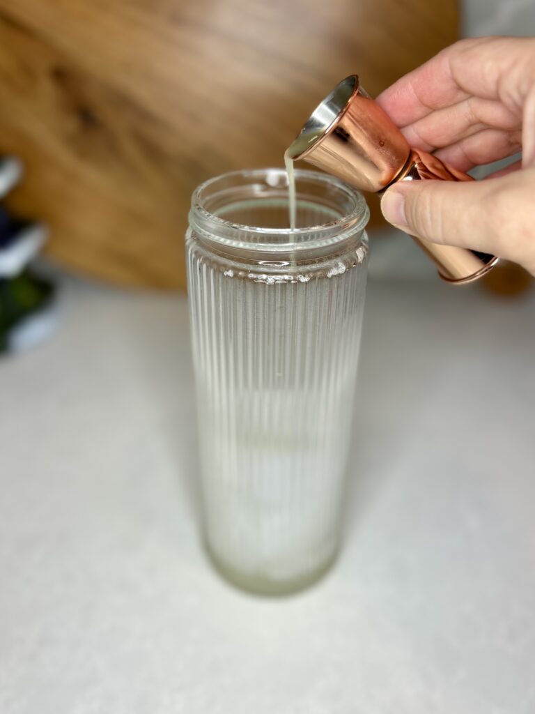 lemon juice being poured in to a cocktail shaker