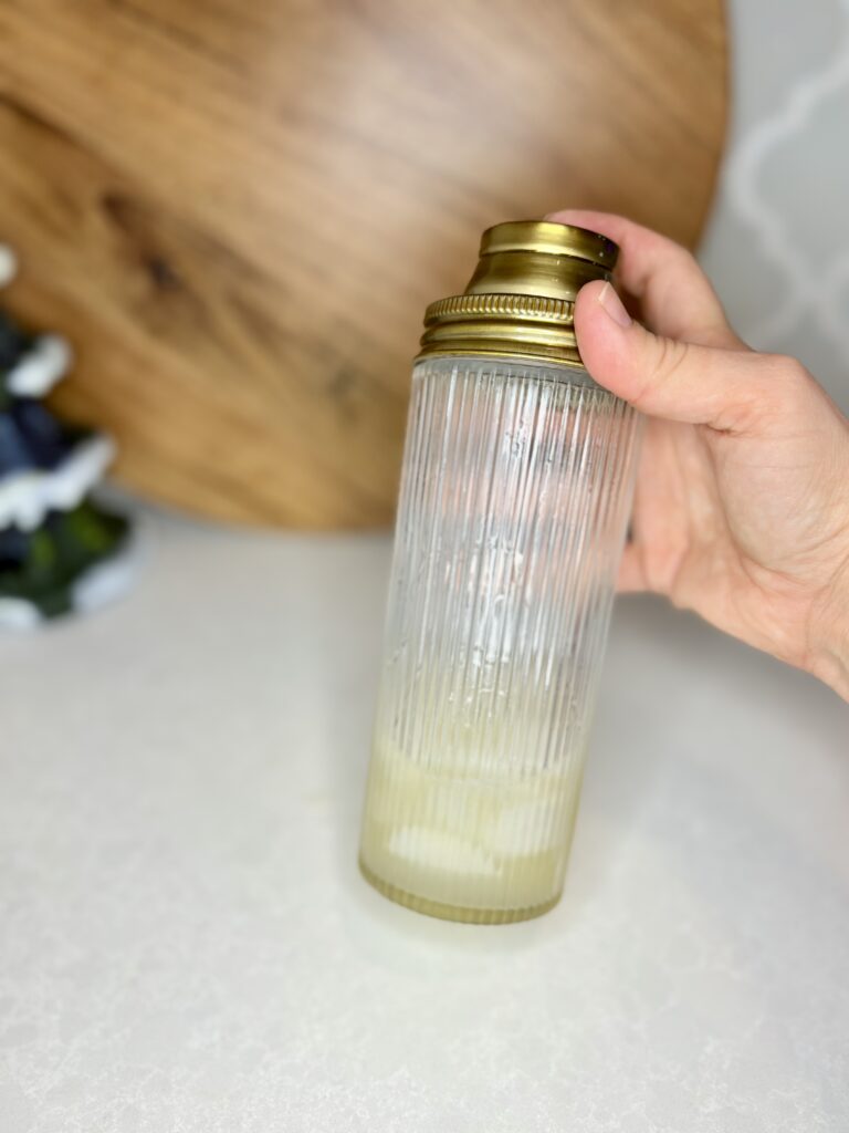 lemon juice, simple syrup, and gin being shaken with ice in a cocktail shaker