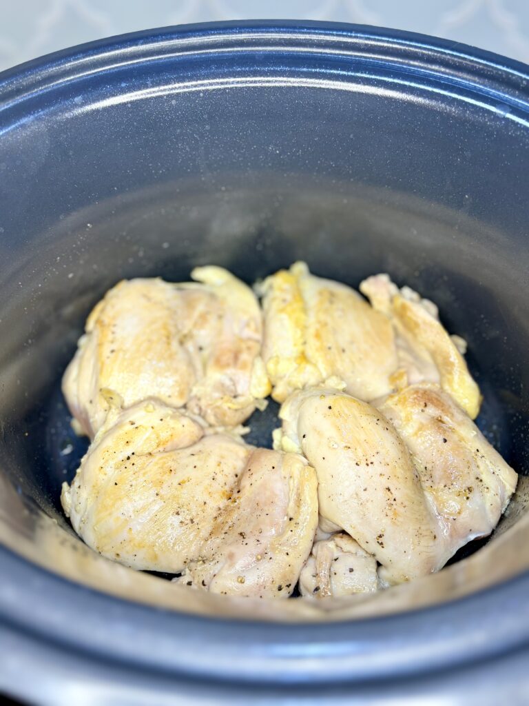 chicken thighs seasoned with salt and pepper being browned in a pot