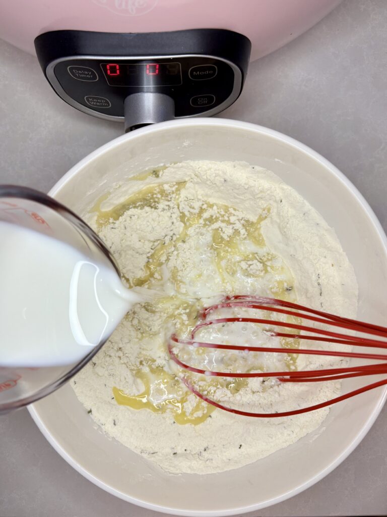 milk being whisked into flour and seasoning mixture in a bowl