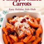 Close-up of glazed carrots topped with shredded cheese and cranberries in a white bowl for holiday side dish.