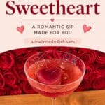 A beautifully styled image featuring a pink cocktail in a coupe glass with a heart-shaped ice cube, set against a backdrop of red roses. The design emphasizes romance, love, and celebration, making it ideal for Valentine's Day, anniversaries, or romantic events. The image highlights the drink's appealing presentation and the theme of love and affection.The Sweetheart Cocktail