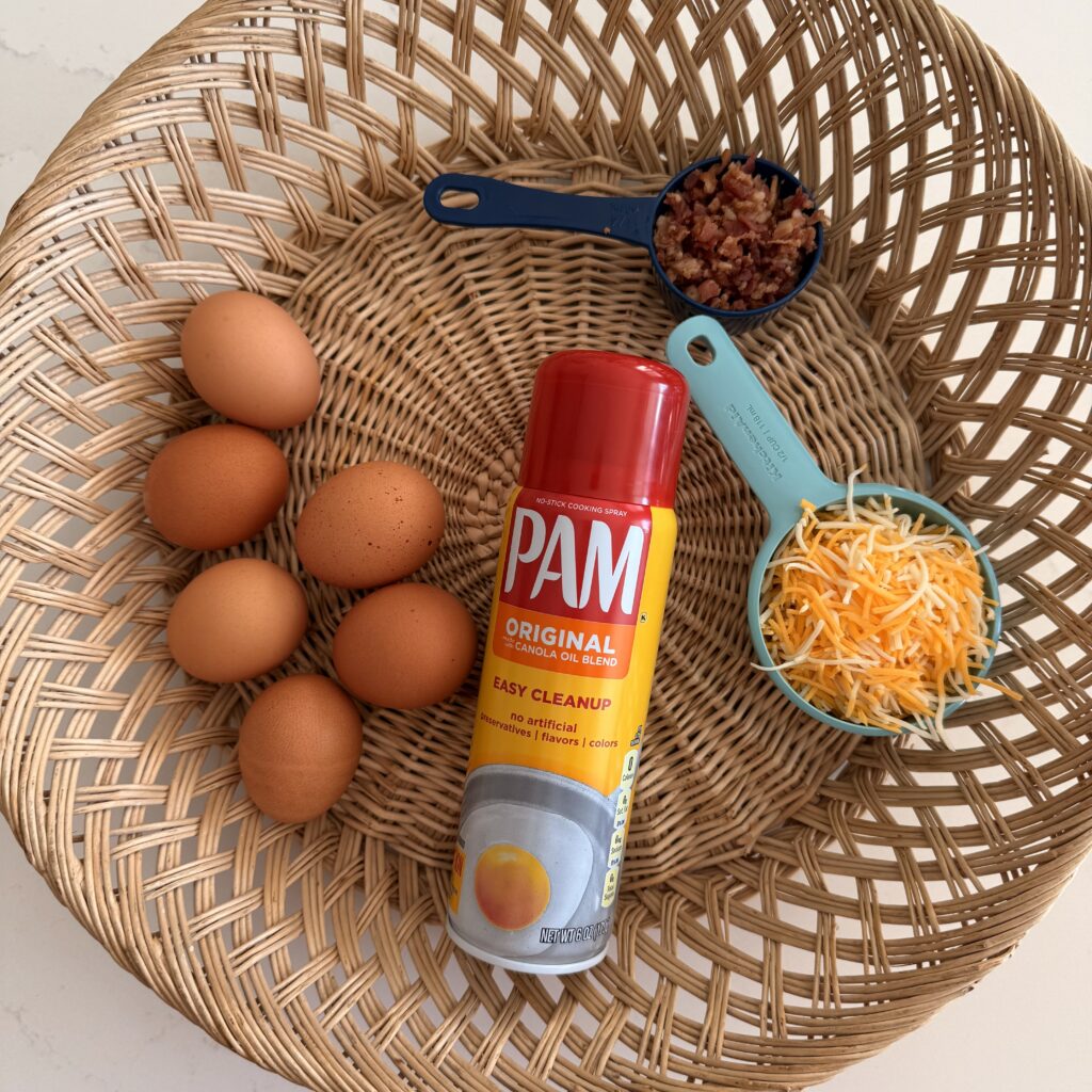 6 eggs, bacon pieces, shredded Colby jack cheese and non stick spray in a basket on the counter.