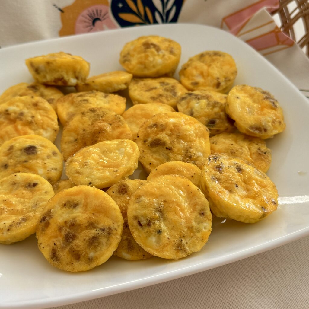 Mini Egg bites on a white plate with a pink and white hand towel in a basket on the counter.