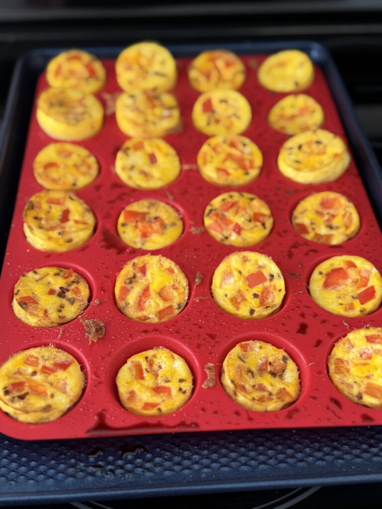 Baked Spicy Red pepper egg bite on a dark blue baking sheet on the oven top.