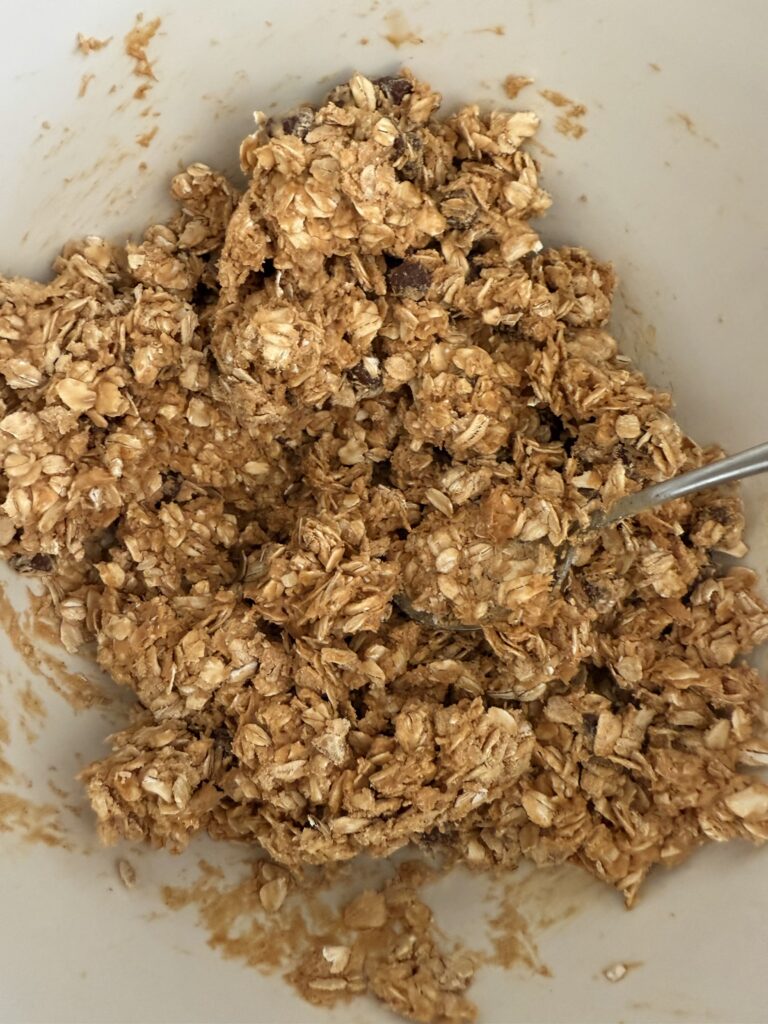 mixed together ingredients in a large white mixing bowl with a spoon on the counter.