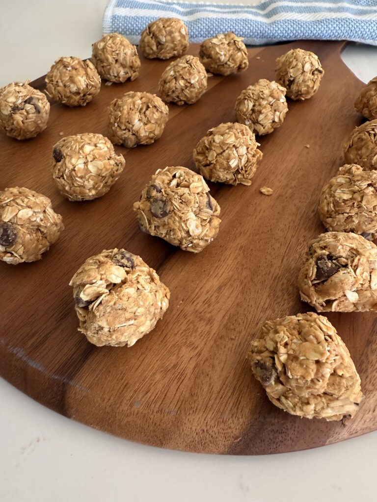 Refrigerated no bake energy bites on a brown round board on the counter.