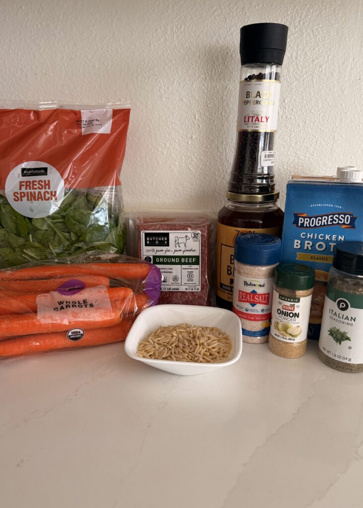 ground beef, Italian seasoning, onion powder, chicken broth, beef broth, spinach (fresh or frozen), carrots, and orzo pasta on the counter.