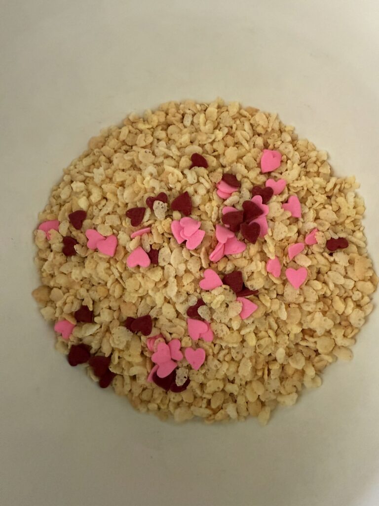 Edible sugar hearts with rice crispy cereal in a large white bowl, on the counter.