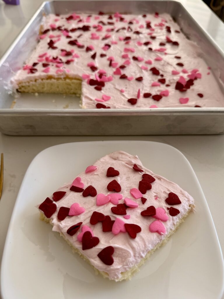 The Queen of Hearts cake is on a white plate, and the rest of the sheet cake is on the counter in the background.