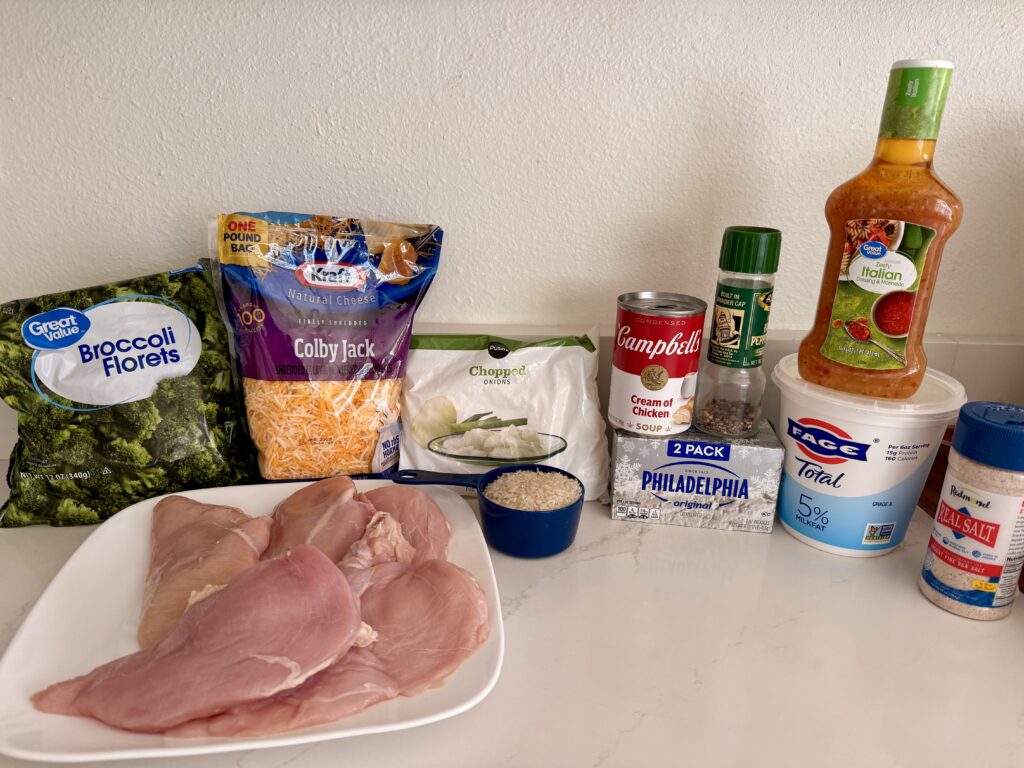 Boneless, skinless chicken breasts, white rice- Long Grain, Italian salad dressing, chicken broth, cream of chicken soup, broccoli florets (fresh or frozen), chopped onion (fresh or frozen), Colby Jack shredded cheese, Philadelphia cream cheese, and salt & pepper on the counter.