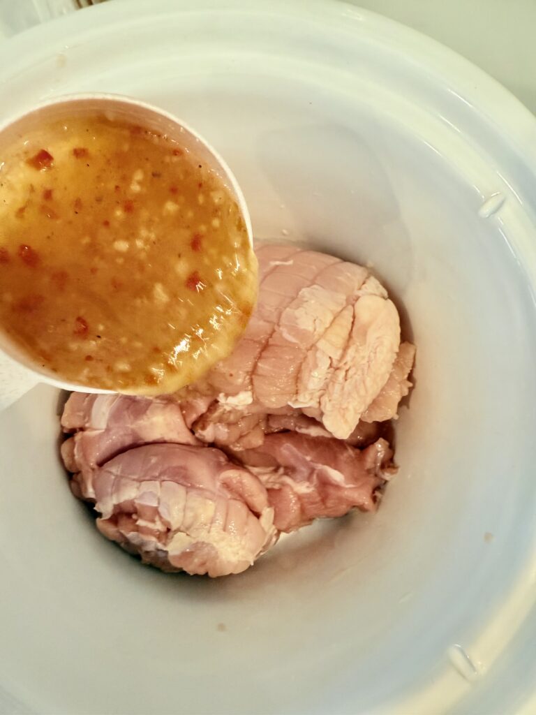 pouring italian salad dressing on top of the turkey meat in the slow cooker. 