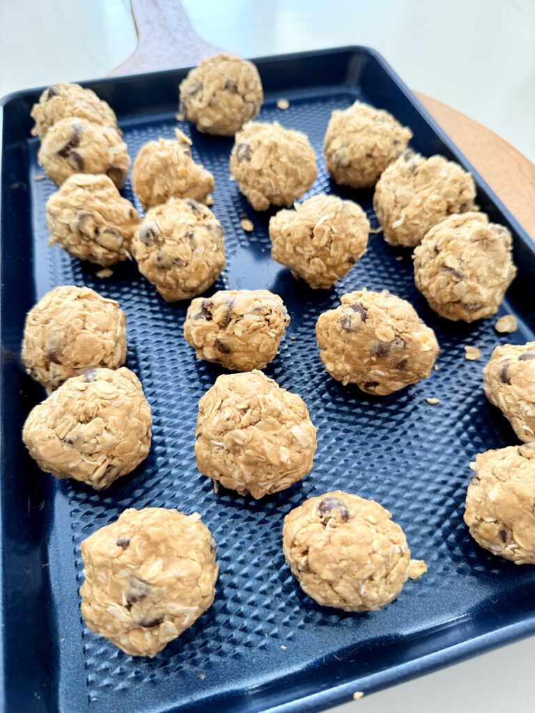 Rolled into balls are the bites on a dark blue baking sheet on the counter