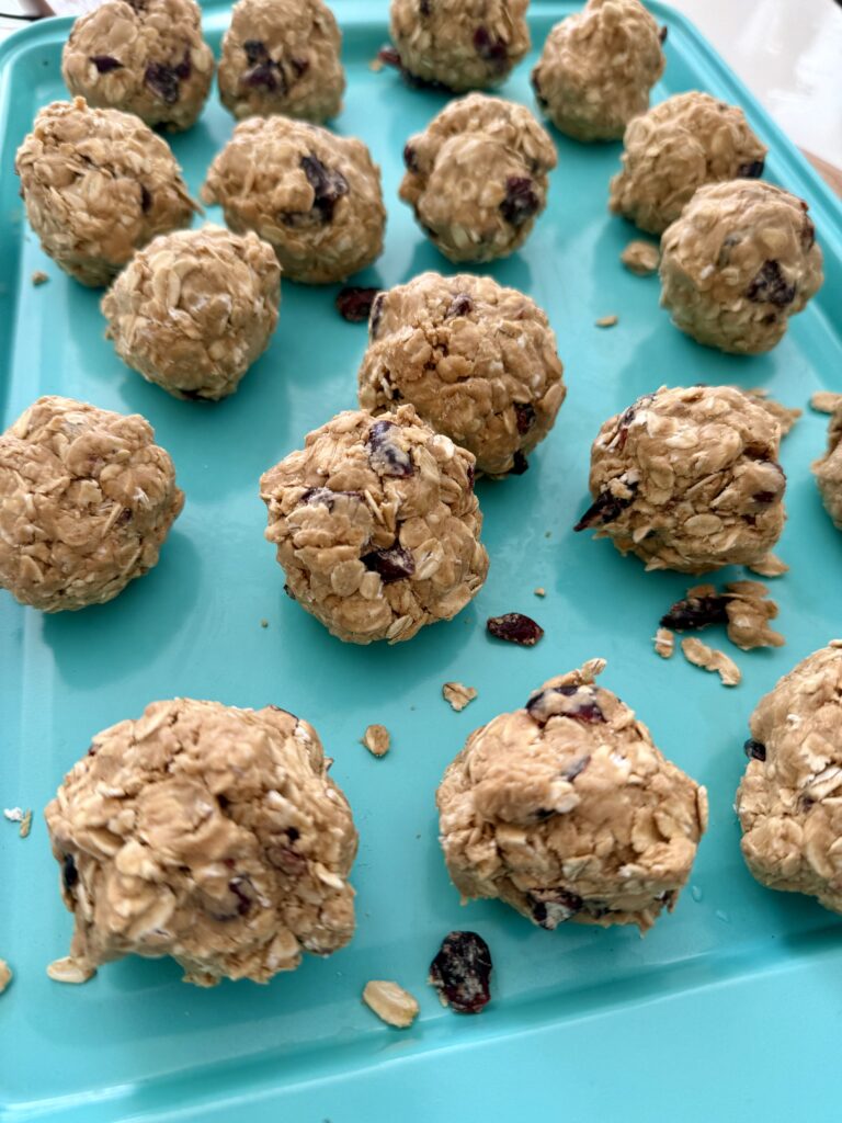 Yummy Cranberry oatmeal bites lined up on a light blue baking sheet on the counter,