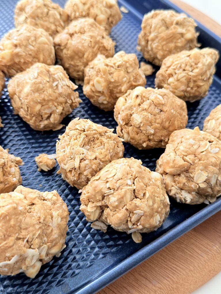 White chocolate and coconut protein bite on a navy blue baking sheet on the counter.