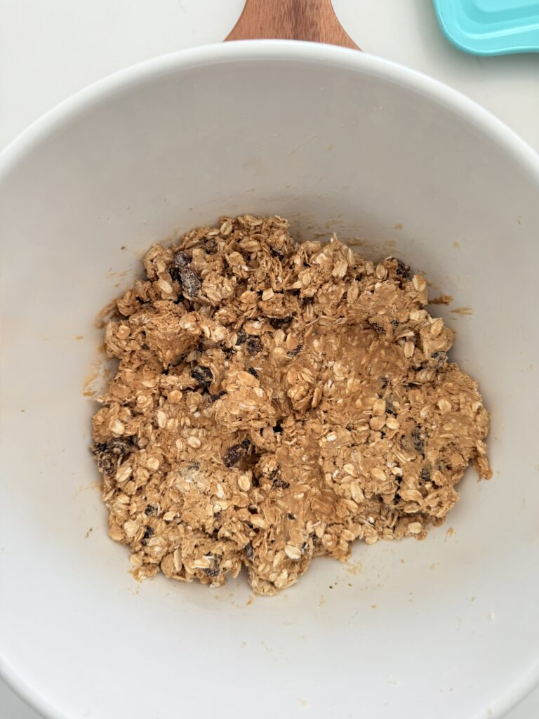 Mixed dough in a large white mixing bowl on a brown cutting board on the counter.