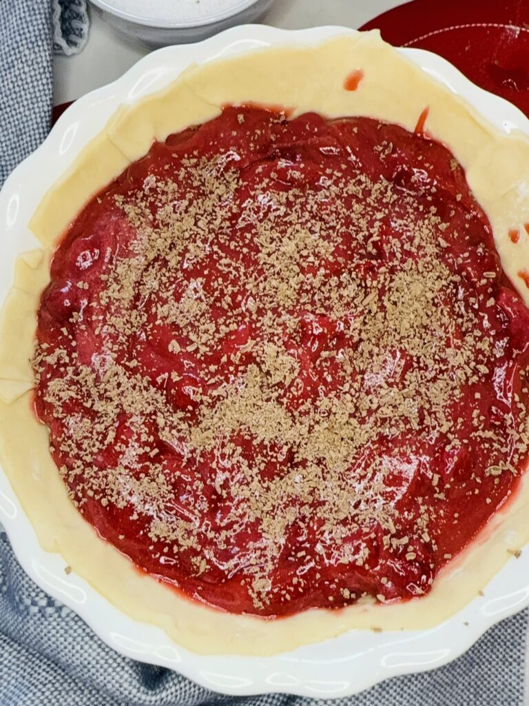 Sugar and grated chocolate sprinkled on top of the pie filling in the pie plate on the counter.