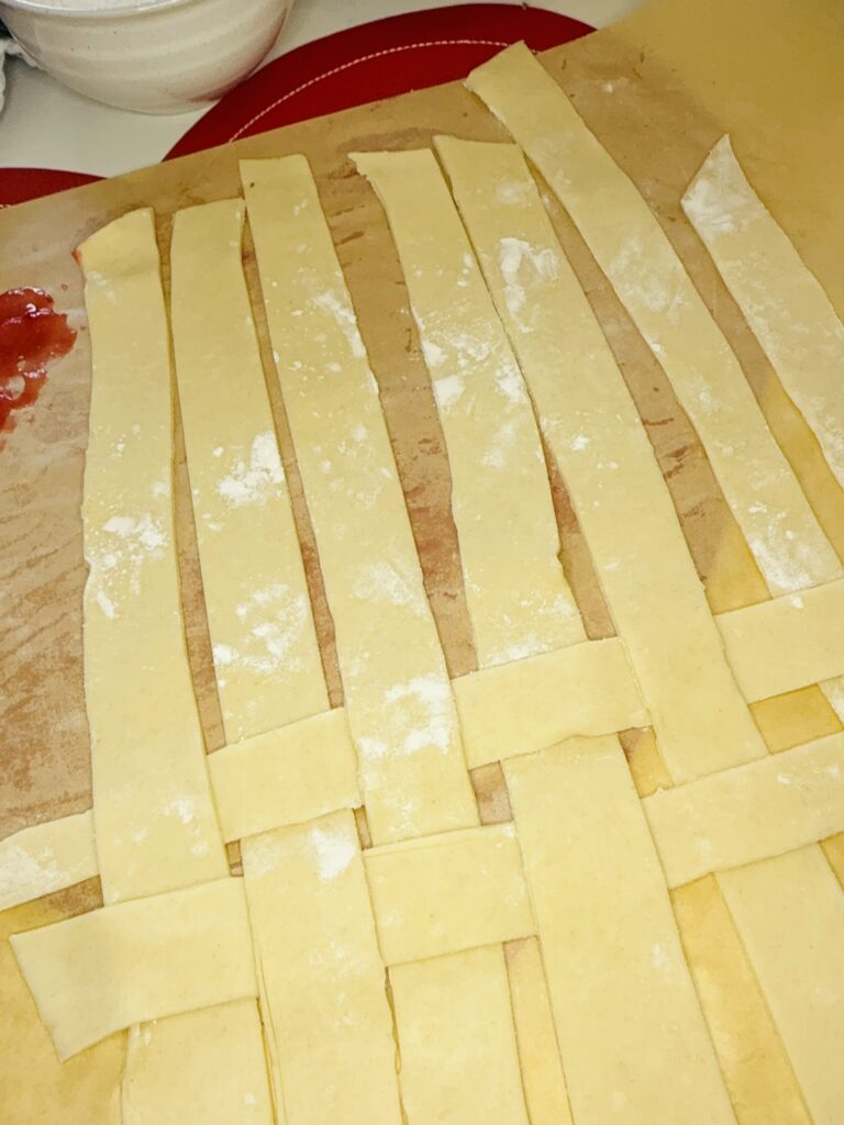 Cut long strips of pie crust on parchment paper on the counter.