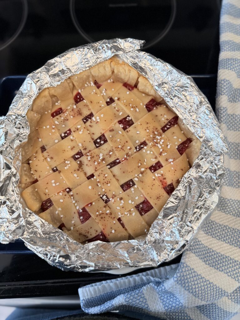 Foil covering the edges of the pie on the black stove top.