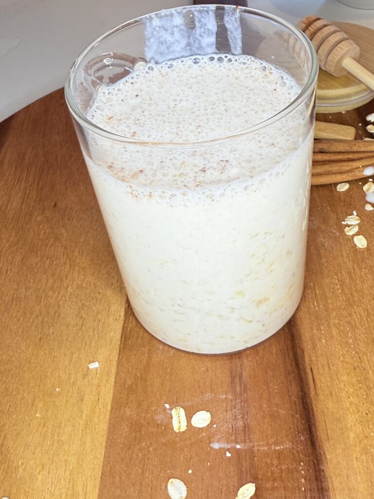 Banana and cinnamon overnight oats in a glass container on a brown cutting board.