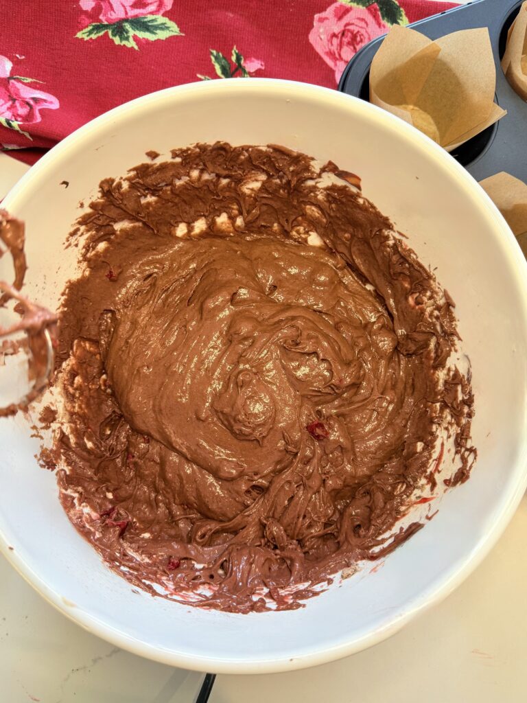 muffin batter in a large white mixing bowl on the counter.