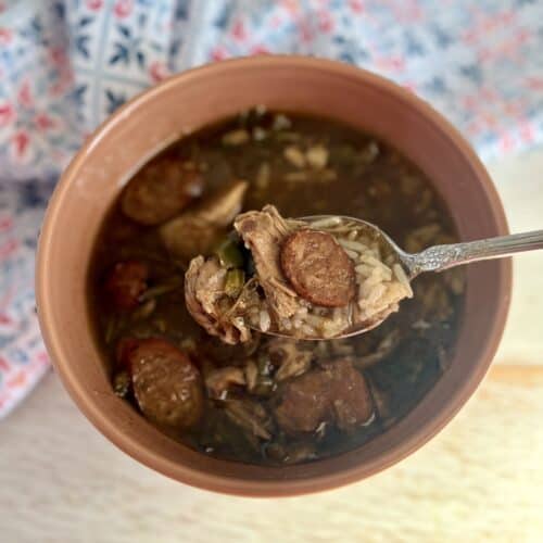 Tender beef stew with sausage and vegetables in a savory broth, served in a rustic clay bowl, perfect for comforting homemade meals and family dinners.