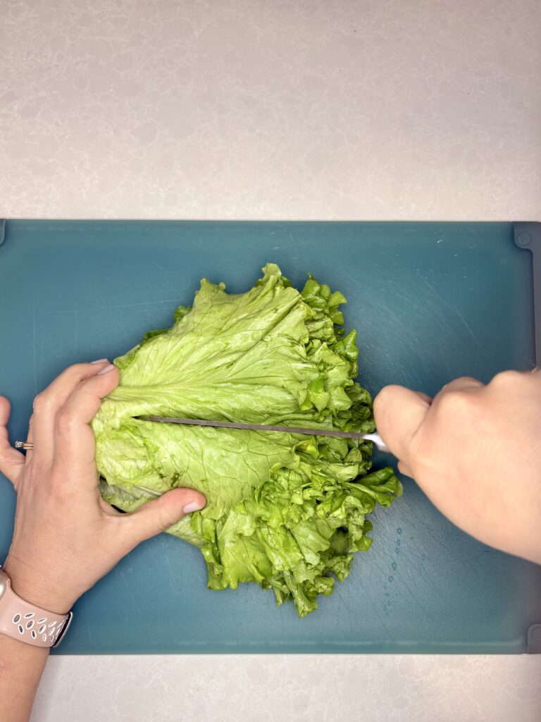 lettuce being sliced long ways on a cutting board with a knife