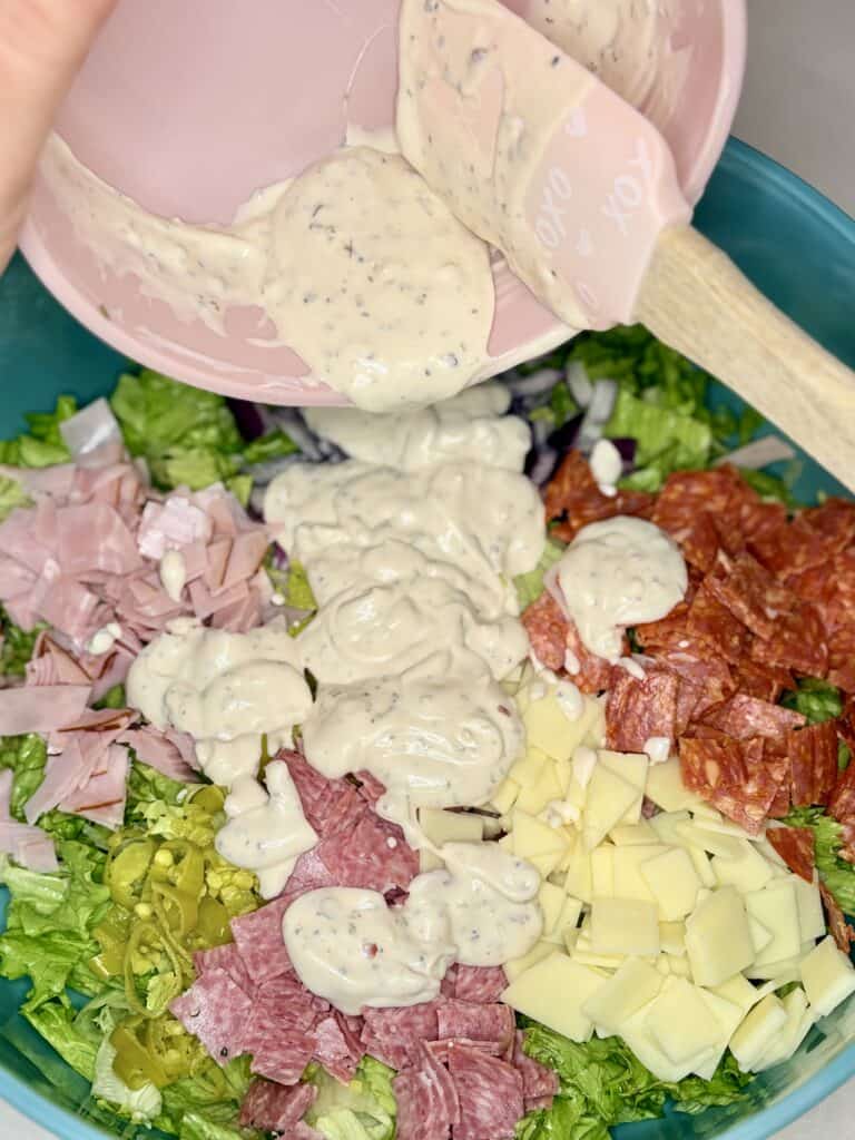 dressing being poured on to salad in a bowl