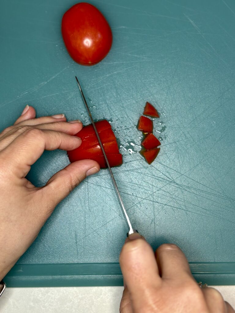 a tomato being diced on a cutting board