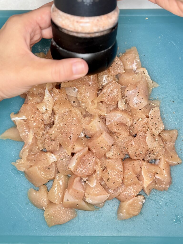 cubes of chicken being seasoned with salt