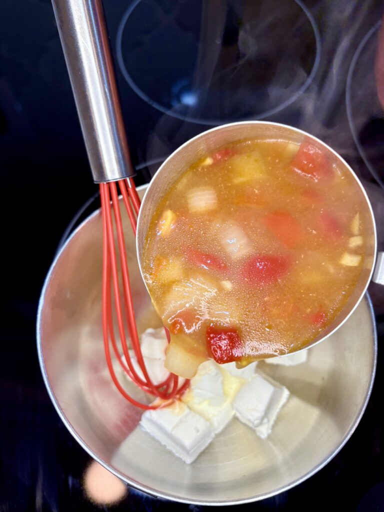 broth being poured in to a bowl with cream cheese