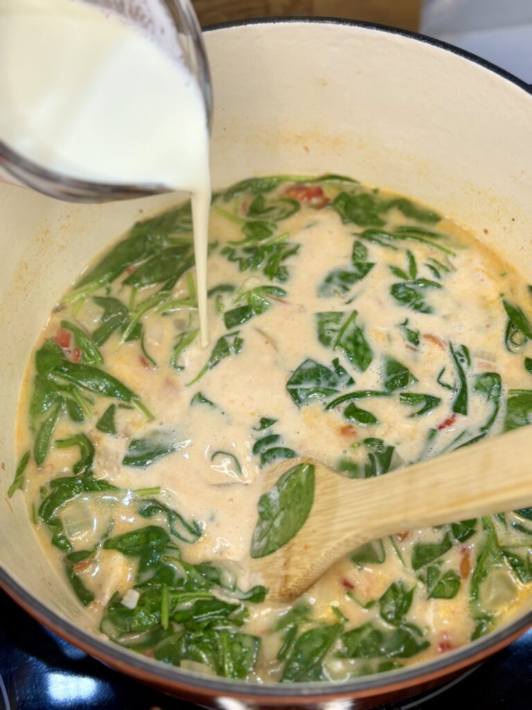 heavy cream being poured into soup pot