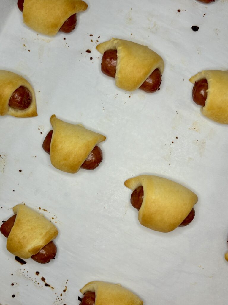 cooked pigs in a blanket on a baking sheet