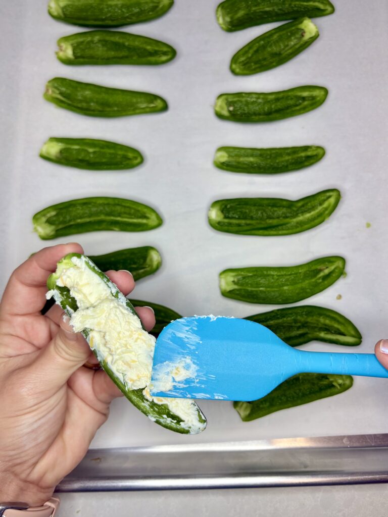 cream cheese misxture being spread on to a jalapeño pepper half 