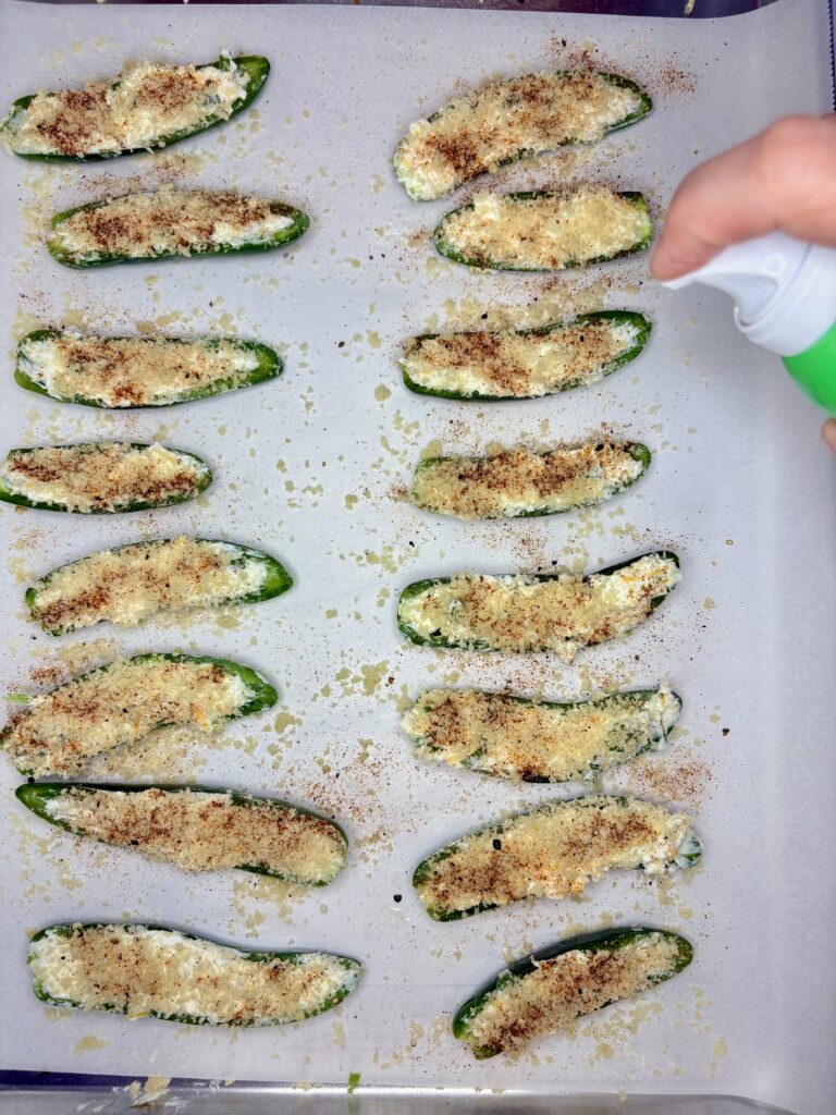 uncooked jalapeño poppers being sprayed with avocado oil