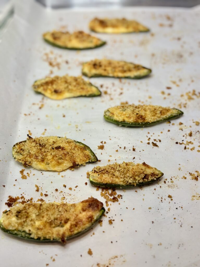 cooked jalapeño poppers on a baking sheet lined with parchment paper