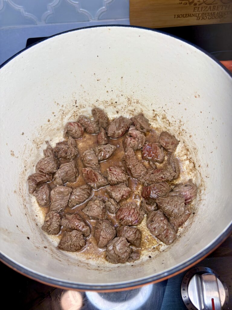 cut up steak being browned in a pot