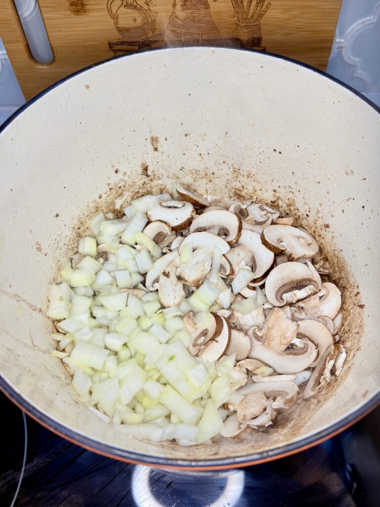 mushrooms and diced onions in a pot on a stove